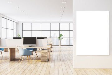 Modern office interior with wooden floors, desks, chairs, and blank vertical canvas on wall near large glass windows overlooking cityscape. 3D Rendering