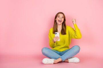 Happy woman in yellow sweater enjoying success with pink background