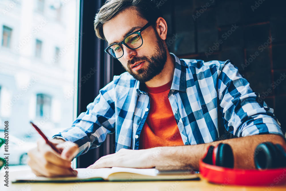 Aufkleber pensive bearded student writing down homework in notepad studying in coworking space.smart hipster g