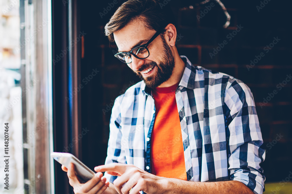Aufkleber cheerful bearded blogger laughing while reading funny comments in social networks on smartphone devi