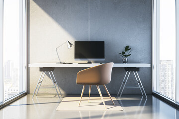 Modern minimalist workspace with desk, chair, computer, and lamp in bright room with concrete walls...