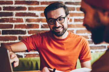 Professional male graphic designer pointing on laptop and explaining task to student.Two hister creative young men collaborating on common project at modern computer connected to 4G internet