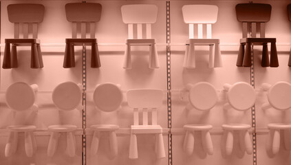 Mocha Mousse - Trendy Color of the Year 2025. Brown and beige plastic children's chairs and stools hang on the wall in the furniture store.
