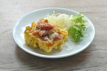 baking macaroni and slice pork bacon with chees topping tomato eat couple salad on plate