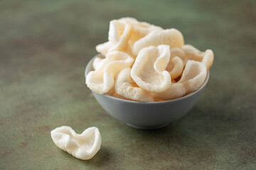 Prawn chips in bowl on green background