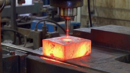 Drilling hot metal ingot in metal factory
