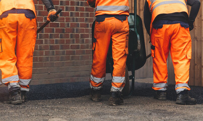 Workers in high visibility clothing laying new asphalt