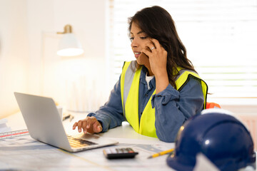 Woman Construction professional engineer engages in remote work while wearing safety gear and using...
