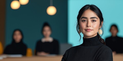 Confident Boss  woman in a black sweater with others blurred behind her.