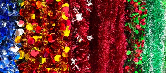 Red, blue and green tinsel close up horizontal photo, bright decoraive background, winter abstract background with Christmas tree decorations