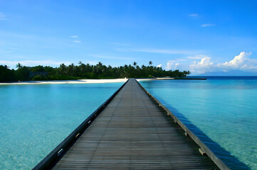 Obraz premium Long wooden pier leading to turquoise ocean and tropical beach