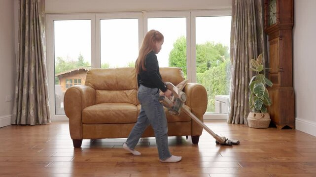 Child helps with household chores by vacuuming living room floor in bright and spacious area
