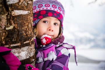 Portrait of preschool girl hugging a tree during Winter in Austria