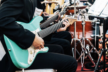 Guitarist male hands playing electric guitar with the band on stage. Classical concert, performance...