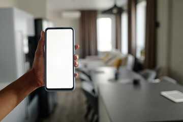 Unrecognizable female hand holding smartphone, blurred apartment in background