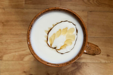 Kefir yoghurt drink drizzled with maple syrup in a brown rustic mug. Homemade kefir
