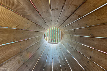 Light at the end of the tunnel. Light shining into a tunnel made of wooden slats in a childrens play area