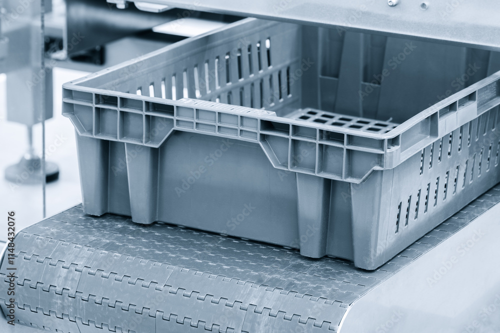 Poster a plastic container is on a conveyor belt. the container is empty