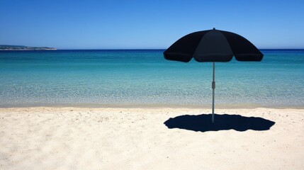 Fototapeta premium Black beach umbrella casting shadow on white sand by turquoise sea.