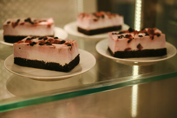 Delicious sponge berry piece of cake on a coffee shop window on a white plate close-up. Sweet dessert behind glass.
