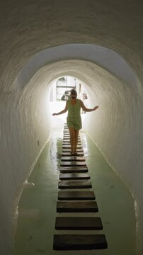Woman walking on stepping stones in water tunnel at lagomar lanzarote canary islands wearing sunglasses and summer outfit