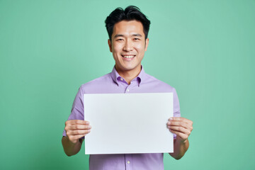 An advertisement studio template portrait photo of a person: a man with a bright smile on his face, holding a blank white sign in his hands against a green background.