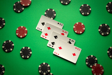 On a bright green table lie poker cards with a combination of two pairs and chips from the winnings or bets