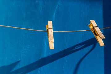 Two Wooden Clothespins on a Clothesline with a Blue Background and Shadow