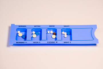 Blue and white pills in dispenser for daily consumption. Medical devices. Close-up of pills.