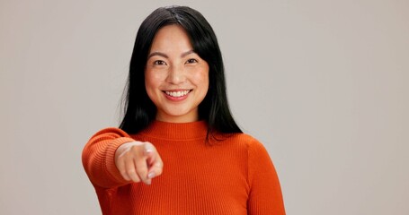 Asian woman, portrait and point at you in studio with smile, choice and hiring by background. Girl, person and happy with call to action, recruitment and decision for human resources agency in Taiwan