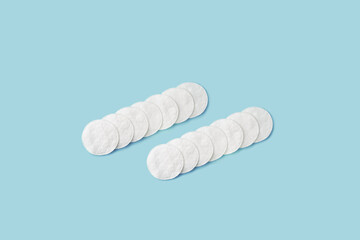 Organic white cotton pads on pastel blue background. Concept of hygiene, medicine, health care and beauty, top view
