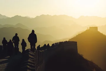  Silhouettes of people walking along the Great Wall at sunset. The mountains create a stunning backdrop that adds to the serene atmosphere. Generative AI © Olsek