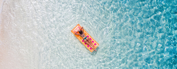 Top above high angle aerial drone view of fit slim sporty attractive girl floating lying on rubber mattress clean clear pure natural sea water enjoy joy calm tranquil relax life lifestyle destination