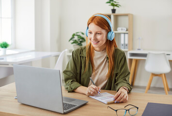 Friendly woman, either a student or freelancer, participates in an online video call using her...