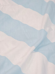 Close-up of a soft fabric with light blue and white wavy stripes, evoking a breezy, nautical, or...