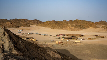 Exploring the Isolated Desert Landscape: Rugged Mountains, Sandy Terrain, and Nomadic Structures Under a Clear Sky, Capturing the Remote and Traditional Lifestyle of a Nomadic Community