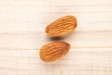 Fragrant roasted almonds with kitchen utensils on a wooden table, close-up, top view.