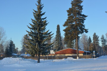 Beautiful winter streets, alleys with roads, cars, cyclists, sidewalks, green fir trees, birches, trees, covered with white, fluffy snow. Infrastructure, Varkaus, Finland. 