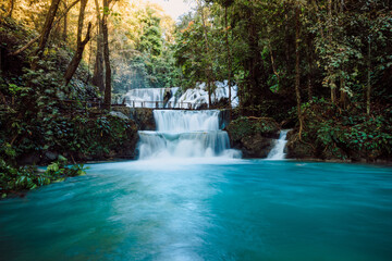 Obraz premium Scenic cascade waterfalls with clear blue water and wooden bridge in Central Sulawesi