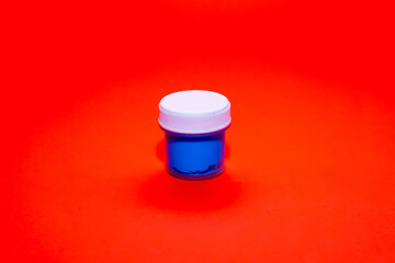 Bright blue paint in a container on a vivid red background