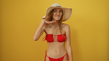 Young, blonde, caucasian, woman, wearing, red, bikini, and, sunhat, making, neck-cut, gesture, against, isolated, yellow, background