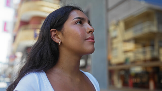 Attractive hispanic young woman walking outdoors in urban city setting during daytime