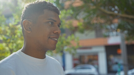 Young, hispanic, man smiling in an urban park on a sunny day capturing the essence of city life outdoors