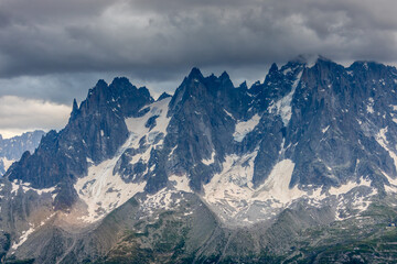 Obraz premium Nasty weather in the Alps. Dark cloudy sky and overcast before the rain and storm. Stormy weather. Snow and rocky summits of the alpine peaks inside the cloud. Aiguilles du Chamonix in autumn 