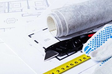 Laying flooring. Linoleum, a knife and a house plan on the builder's table. Taking measurements for laying the floor..