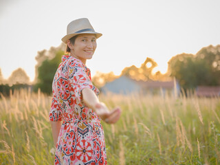 Young woman walking through picturesque European field in late summer. Golden sunlight, lush...