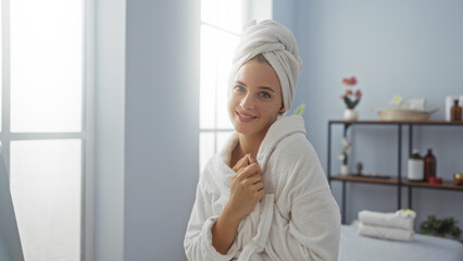 Woman relaxing at a spa wrapped in a towel, smiling with a serene expression in a bright, peaceful...