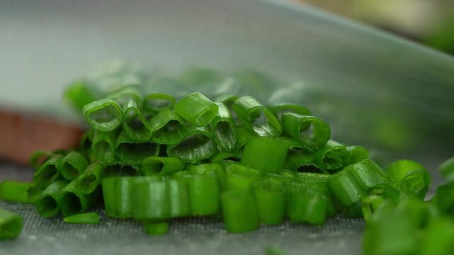 Close up of chefs hands cut fresh green onions with kitchen knife. Cooking concept with greens. Greens, vegetables. Cooking food