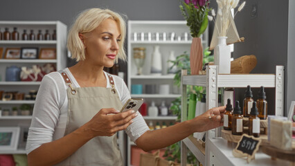 Woman shopping in decor store holding phone looking at items on shelf surrounded by various decor objects and home products in a stylish indoor setting