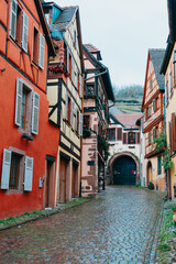 Small narrow cobblestone alleyway in Kaysersberg France on a rainy day, some half timbered homes decorated for Christmas